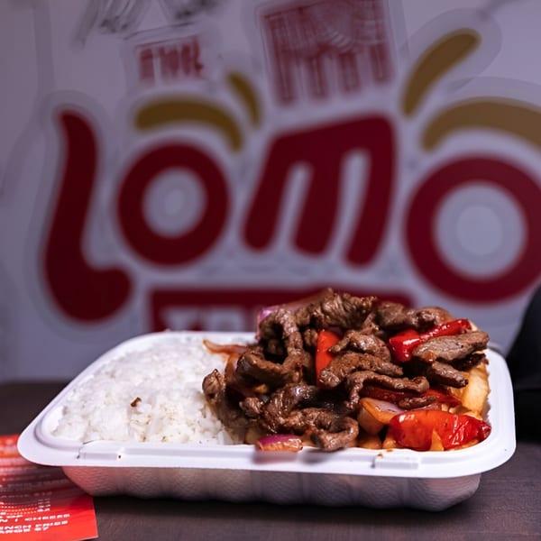 Peruvian Lomo Saltado with rice in a takeout container, with the Lomo Truck logo in the background.