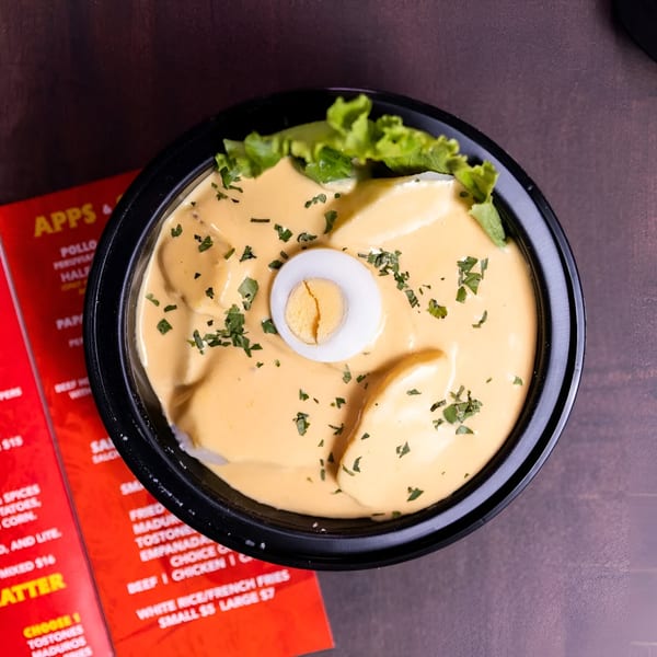 Peruvian Papa a la Huancaína with yellow sauce, parsley, lettuce, and a hard-boiled egg.