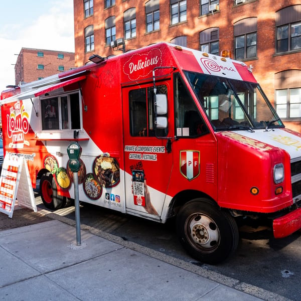 Lomo Truck's red and white food truck, featuring Peruvian cuisine, parked on a city street.