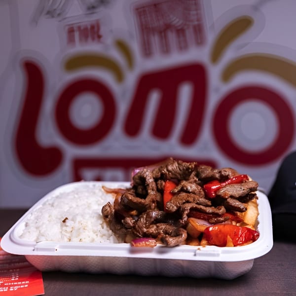 Lomo Saltado with rice in a takeout container, with the Lomo Truck logo blurred in the background.
