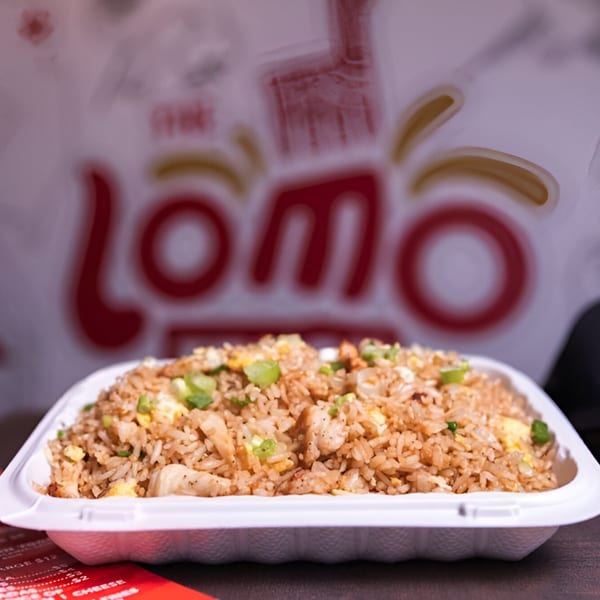 Peruvian fried rice with chicken, egg, and green onions in a white takeout container.