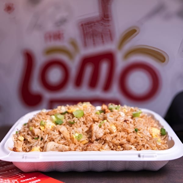 A white takeout container filled with Peruvian fried rice, chicken, egg, and green onions.